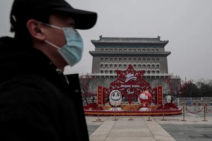 Un hombre con tapabocas camina cerca de las mascotas de los Juegos Olímpicos y Paralímpicos de Invierno de Pekín 2022, en China.