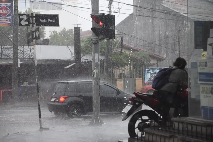 Conductores de motos y automóviles bajo la lluvia en Asunción.