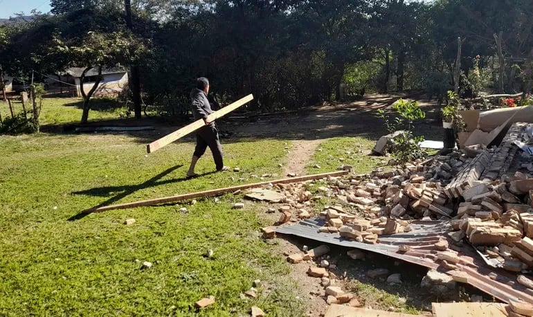 Don Juan Báez intenta recuperar algunos materiales luego de que personas que dijeron ser efectivos policiales y militares derrumbaran parte de su vivienda en la zona de Mbatovi.
