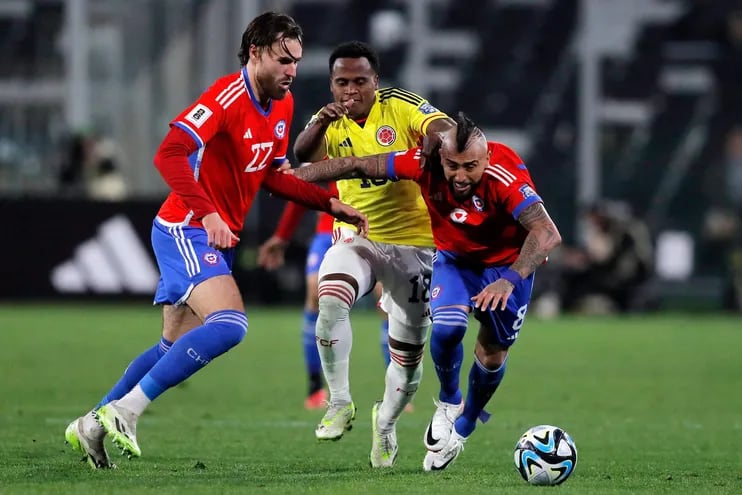 Arturo Vidal (d) toma carrera en procura del balón ante su compañero Ben Brereton y el colombiano Jhon Arias, durante el partido que Chile y Colombia empataron sin goles.