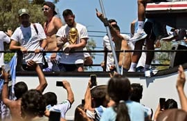 Lionel Messi de Argentina saluda a los fanáticos que sostienen el Trofeo de la Copa Mundial de la FIFA mientras el equipo desfila a bordo de un autobús después de ganar el torneo de la Copa Mundial de Qatar 2022 en Buenos Aires, Argentina el 20 de diciembre de 2022.