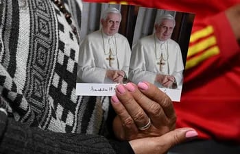 A believer holds a photo of Pope Emeritus Benedict XVI during the eucharist in the Primada Cathedral on the eve of the late pontiff's funeral in Bogota on January 5, 2023. (Photo by Raul ARBOLEDA / AFP)