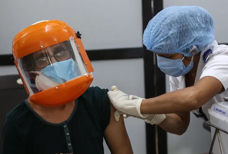 Un hombre con escafandra recibe su primera dosis de la vacuna contra el Covid-19, fabricada por el Instituto Serum de la India, en el vacunatorio del hospital Shatabdi, en Bombai, India.