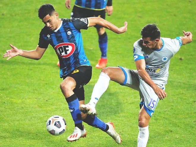 El “Topo” Cáceres, uno de los puntos altos en la marca del 12 de Octubre, no le da tregua en la puja por la pelota a Maximiliano Rodríguez de Huachipato. AFP