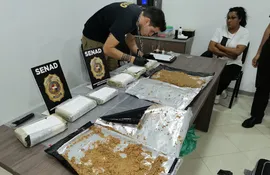 La aprehendida Lidia Ramírez Quintana observa a un agente de la Senad analizar los "panes" de cocaína que fueron encontrados dentro de su maleta, en el aeropuerto internacional "Silvio Pettirossi".
