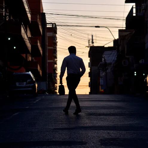Un hombre cruza la calle, mientras amanece en Asunción.