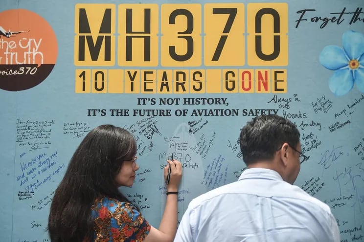Una mujer escribe un mensaje en un mural en conmemoración del décimo aniversario de la desaparición del vuelo MH370, el pasado domingo en Pekín, China.