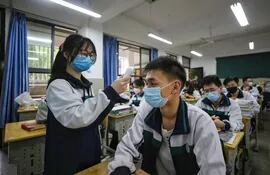 Una estudiante de último año de secundaria verifica la temperatura corporal de sus compañeros de clase antes de una clase en Wuhan, en la provincia central de Hubei, China