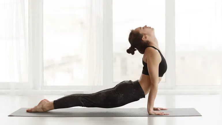 Una mujer hace la postura de la cobra en un mat de yoga