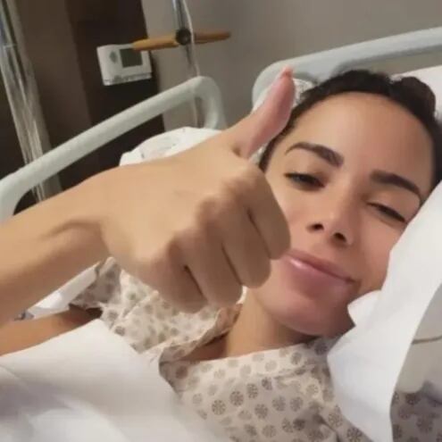 Anitta levantando el pulgar derecho en su cama de hospital, indicando que todo está bien.