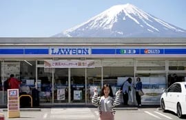 Una turista extranjera posa frente a una tienda de convencia Lawson con el Monte Fuji detrás en Fujikawaguchiko.