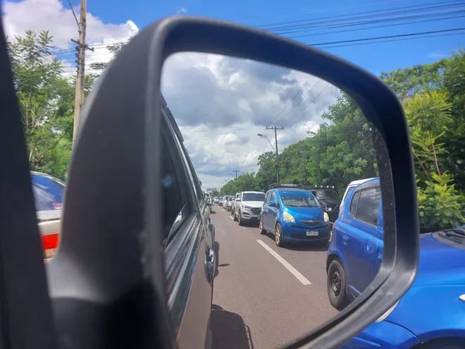 A través de un espejo retrovisor se observan a numerosos vehículos aguardando llegar al puesto de peaje de Ypacaraí. Están en el carril de salida en el sentido Ypacaraí-Caacupé.