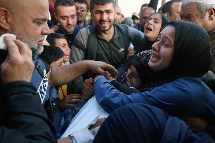 The widow (R) of Hamza Wael Dahdouh, a journalist with the Al Jazeera television network, and his father Al Jazeera's bureau chief in Gaza, Wael Al-Dahdouh (L) mourn over his body during his funeral, after he was killed in a reported Israeli air strike, in Rafah in the Gaza Strip on January 7, 2024. Dahdouh, who was himself wounded in the arm, lost his wife and two other children in Israeli bombardment in the initial weeks of the war. (Photo by AFP)