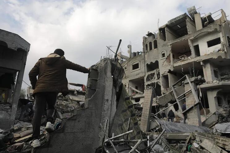 Un hombre busca entre los escombros de un edificio destruido por un bombardeo israelí en el sur de la Franja de Gaza, este lunes.
