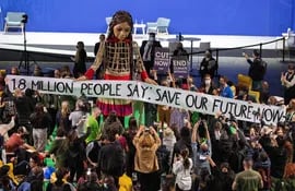 Delegados y participantes de la COP26 rodean a la muñea "Pequeña Amal", en Glasgow.