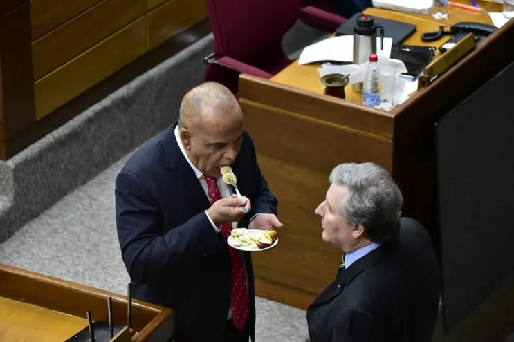 El senador cartista Basilio "Bachi" Núñez come una banana fileteada en la Cámara de Senadores. Frente a él, su colega Rafael Filizzola.