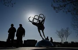 Gente camina cerca de una estatua con los anillos olímpicos, en las inmediaciones del Comité Organizador de Pekín, en Shougang Park, una de las sedes para los Juegos Olímpicos de Invierno de Pekín 2022. (Imagen por Noel Celis / AFP)