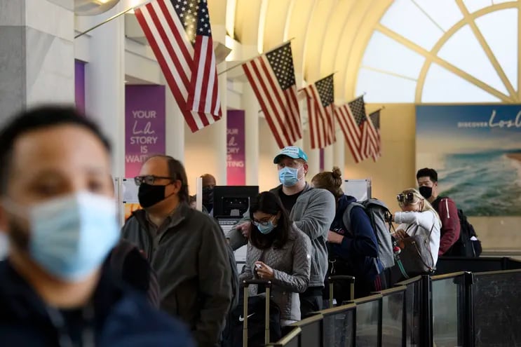 Pasajeros con mascarillas en fila en el aeropuerto internacional de Los Ángeles, California.