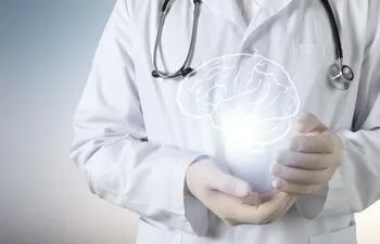 Un profesional de la salud con bata blanca y un estetoscopio alrededor del cuello con la imagen de un cerebro dibujada entre las manos.