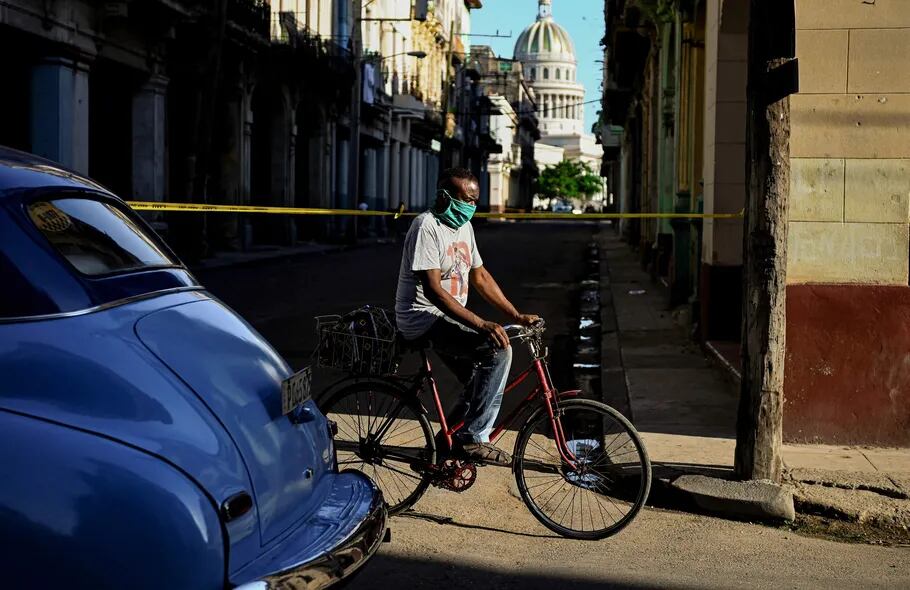 Un hombre con tapabocas se moviliza en bici en La Habana vieja, Cuba.
