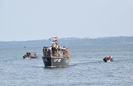 La procesión náutica a través del río Paraná a bordo de una patrullera de la Prefectura Naval de Itapúa, escoltada por embarcaciones menores, en el marco de un atractivo paisaje.