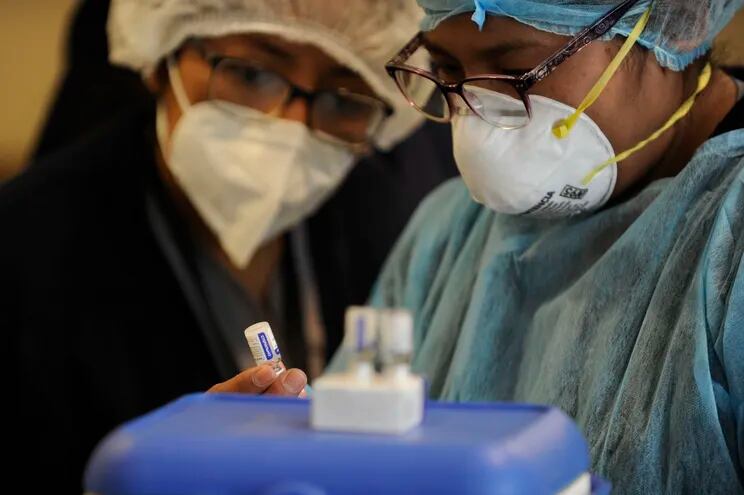 Trabajadores médicos observan un recipiente de la vacuna Sputnik V en el hospital Cotahuma de La Paz, Bolivia.