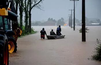 Fotografía cedida por el ayuntamiento que muestra a un grupo de personas que se transportan en una canoa en una calle inundada este miércoles, en Santa María, Estado de Río Grande del Sur (Brasil).
