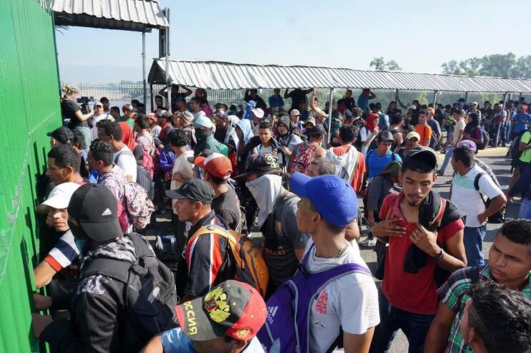 Migrantes hondureños esperan ser atendidos por autoridades del Instituto Nacional de Migración de México este sábado, luego de arribar al paso fronterizo con Guatemala de la Ciudad Hidalgo.