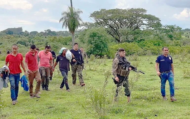 Policías de Antisecuestro custodian a los detenidos en el operativo Sapucái que se hizo ayer en la estancia Indio Cue de Yby Yaú.