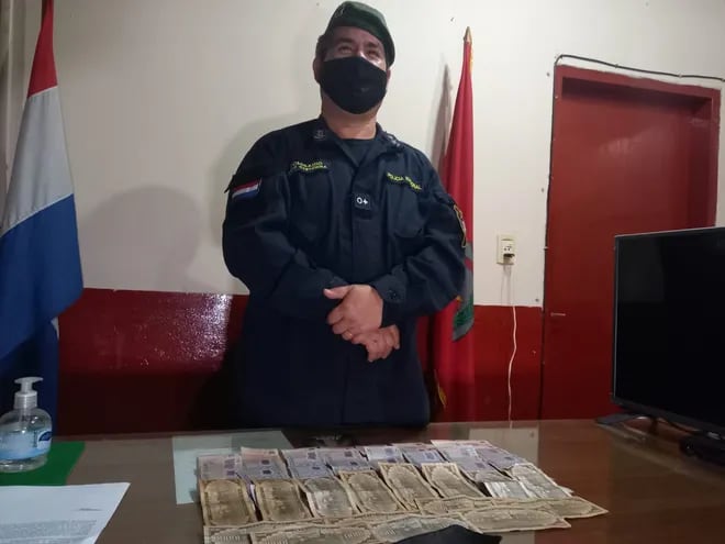Un oficial de la comisaría 9° de la ciudad de Limpio, exhibe los billetes recuperados del poder del detenido.
