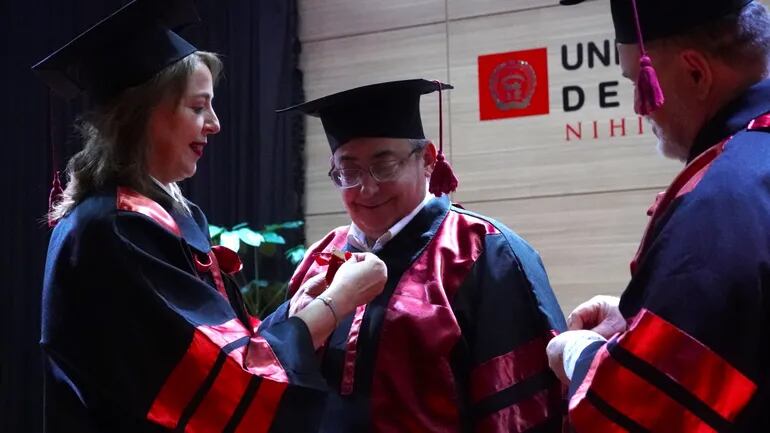 La rectora de la UNAE, acompañada del Vicerrector doctorando Helmut Schaefer, hacen entrega de los símbolos universitarios al Dr. Honoris Causa, Benjamín Barán Cegla.