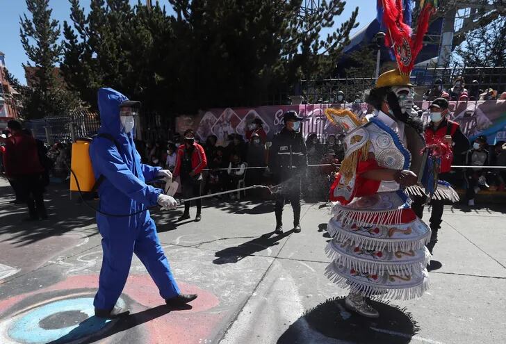 Una persona realiza la desinfección a los bailarines de la "mini" entrada o desfile folclórico que se realiza desde que la pandemia de la covid-19 llegó a Bolivia en marzo del año pasado y que contó con el aval de la alcaldesa de esta urbe, Eva Copa en la ciudad de El Alto (Bolivia). Imagen referencial