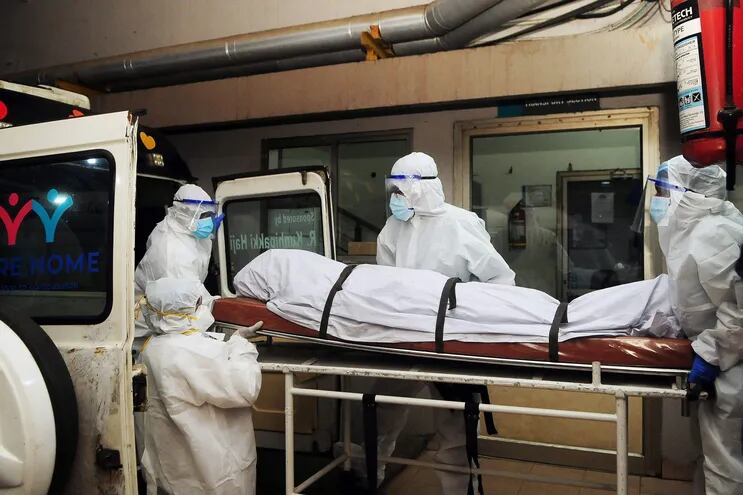 En esta fotografía tomada el 12 de septiembre de 2023, trabajadores sanitarios con equipo de protección mueven el cuerpo de una persona que murió a causa de una infección por el virus Nipah en un hospital privado de Kozikode, en el estado indio de Kerala.