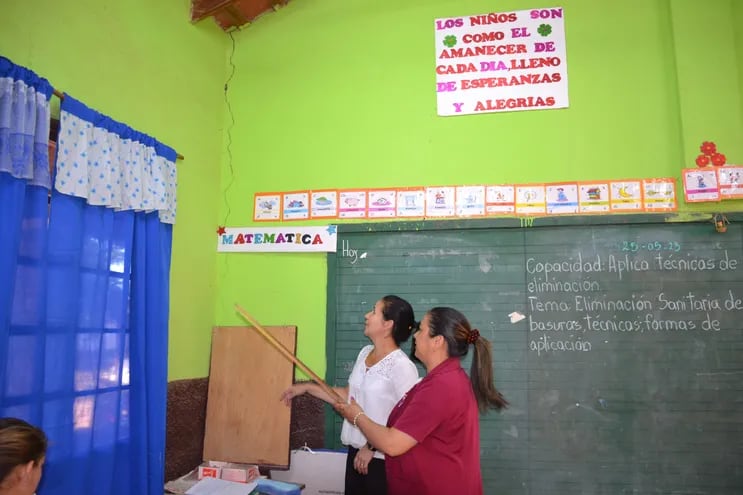 La directora de la Escuela y Colegio Papa Juan XXIII Bertha Maldonado, blusa blanca, y la profesora Rosa Martínez, muestran la grieta de la pared del local de la institución escolar.