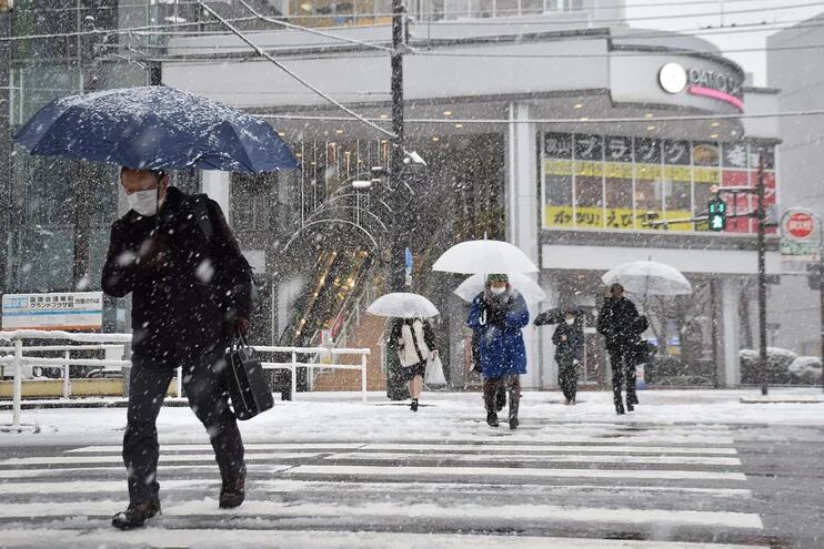 Transeúnes cruzan una avenida bajo una nevada en Toyama, Japón, este martes.