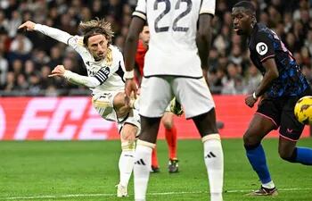 Real Madrid's Croatian midfielder #10 Luka Modric scores his team first goal during the Spanish league football match between Real Madrid CF and Sevilla FC at the Santiago Bernabeu stadium in Madrid on February 25, 2024. (Photo by JAVIER SORIANO / AFP)