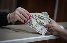 Una empleada entrega billetes de un dólar al comprador en una oficina de cambio, en Río de Janeiro (Brasil). Dólar cae en Brasil a su menor nivel en cinco meses antes de volatilidad  electoral.