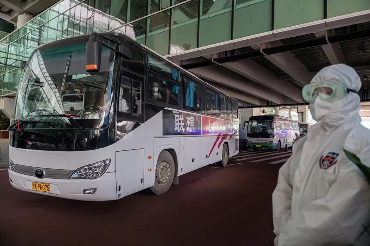 Un bus que transporta a enviados de la OMS sale del aeropuerto de Wuhan, China.
