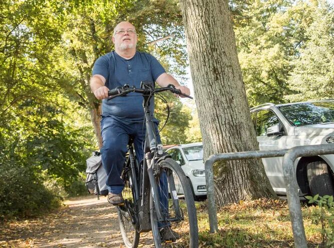 Un hombre barrigón de unos sesenta años pasea en bicicleta al aire libre.