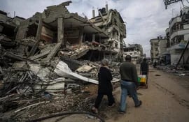 Varias personas pasan junto a edificios destruidos por bombardeos israelíes en el sur de la Franja de Gaza, el martes.
