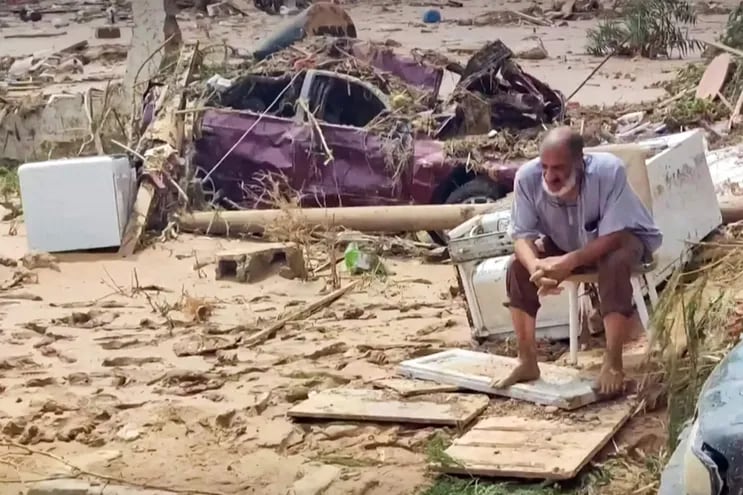 Un hombre sentado entre los daños causados por una inundación generada por la tormenta "Daniel" en Derna, Libia.