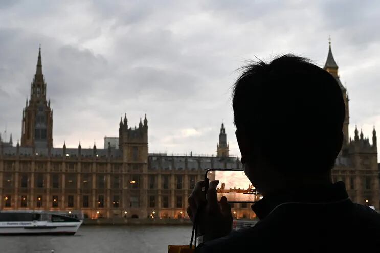 Una persona fotografía el Palacio de Westminster del otro lado del Támesis, mientras espera en la fila en el South Bank para presentar sus respetos ante el ataúd de la reina Isabel II.