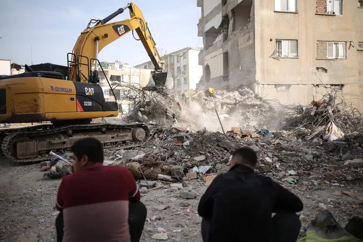 Dos personas descansan frente a los escombros de un edificio colapsado por el terremoto del pasado 6 de febrero, en la ciudad de Adiyaman, Turquía.