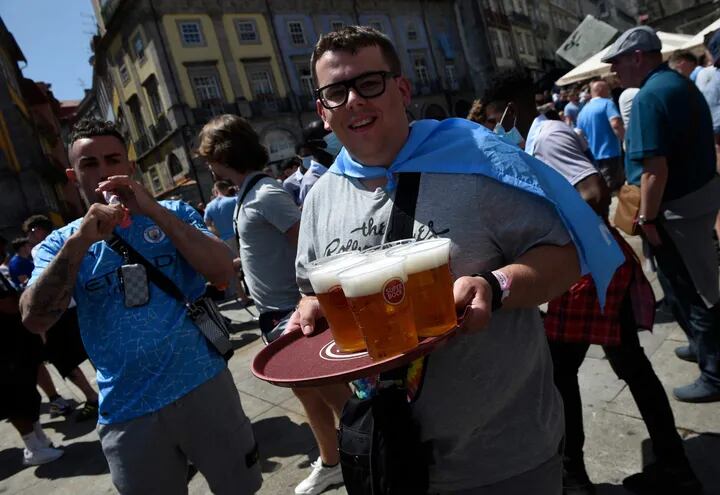 Un hincha del Manchester City carga una bandeja con vasos de cerveza.