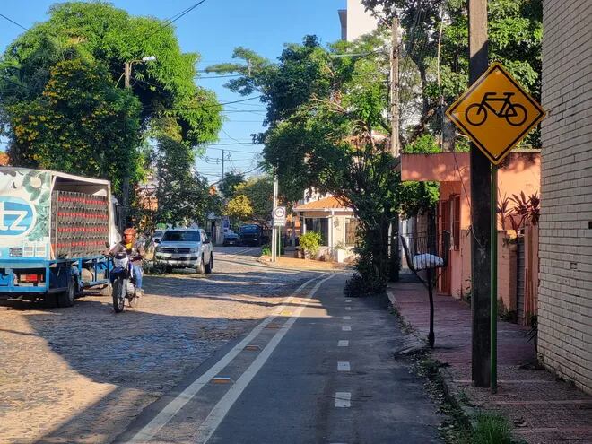 Convivencia. Por esta calle empedrada pasa una bicisenda señalizada y se puede ver también una moto, un camión y un automóvil.