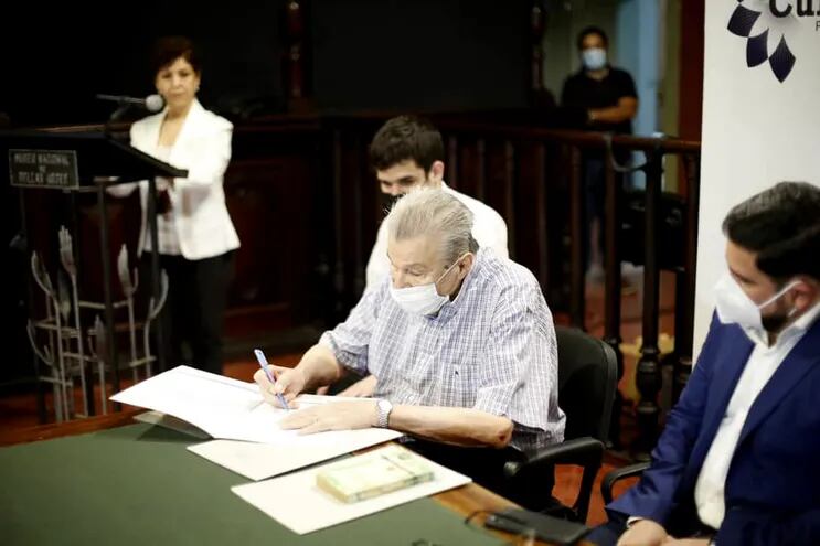 Ignacio Soler Blanc, hijo del pintor Ignacio Núñez Soler, firma los documentos vinculados a la donación. Lo acompaña el ministro de la SNC, Rubén Capdevila.