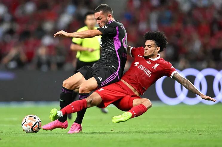 El colombiano Luis Díaz (d), del Liverpool, se tira a los pies del alemán Arijon Ibrahimovic, del Bayern Munich, durante el partido amistoso disputado ayer en Singapur.