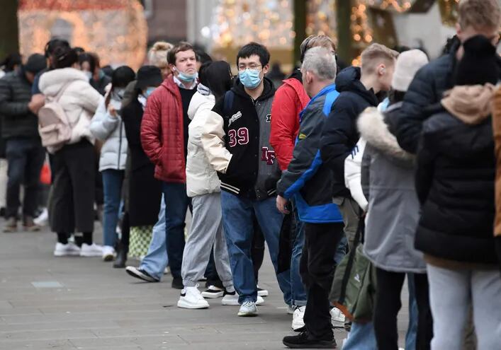 Decenas de personas hacen filas para recibir sus inmunizantes, en Manchester, Reino Unido.