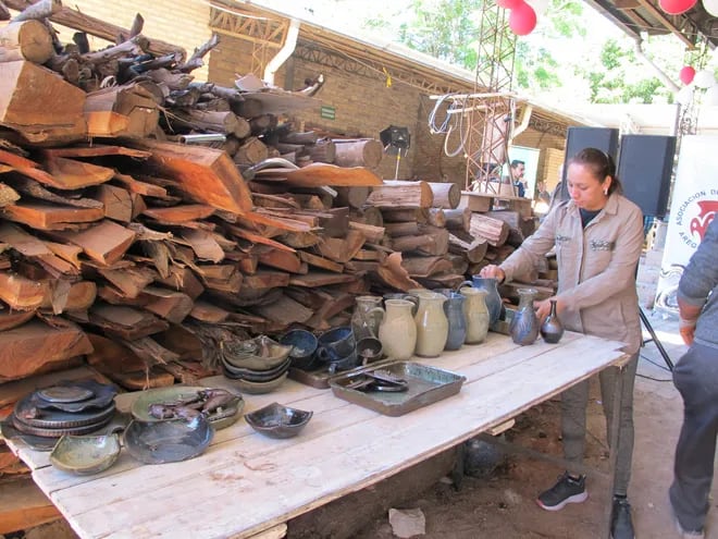 mujer colocando piezas de cerámica esmaltada, al costado leñas