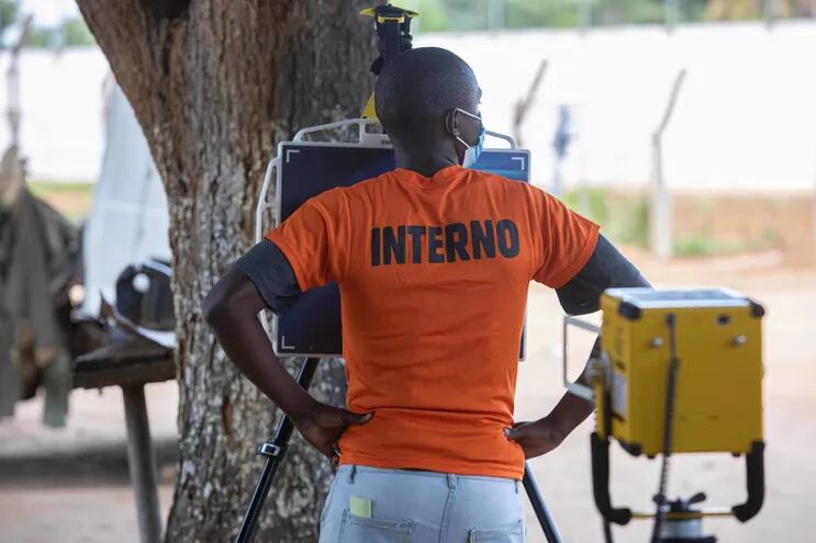En el patio de una prisión de máxima seguridad de la capital de Mozambique, un detenido espera delante de un trípode del que cuelga una tableta blanca, mientras que un enfermero se ocupa de la otra parte del aparato de rayos X portátil, vinculado a un programa de inteligencia artificial considerado como un avance en la lucha contra la tuberculosis.